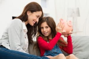 Mother Looking At Daughter Holding Piggybank