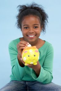 Girl putting coin into piggybank