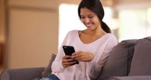 woman using a smart phone sitting on couch
