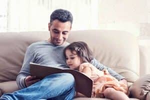 Father reading to daughter at home