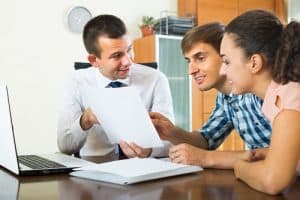 Financial agent explaining details of contract young couple in office