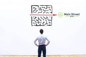 a man looking at a maze with an arrow in the middle pointing to MSB logo
