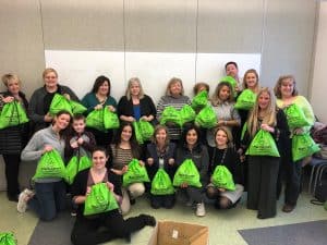 Group of Main Street Bank employees with drawstring bags filled with donation items for homeless shelters