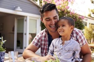 Father And Son Eating Outdoor Meal In Garden Together