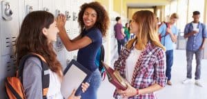 Teenage students gathered at lockers with backpacks and notebooks