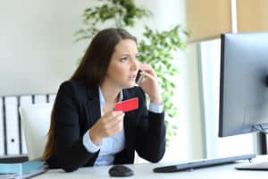 Worried executive holding credit card claiming on phone at office