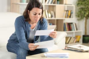 Serious adult woman looking at letters at home