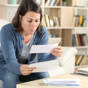 Serious adult woman looking at letters at home