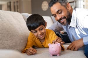 Father and Child putting coins into a piggy bank