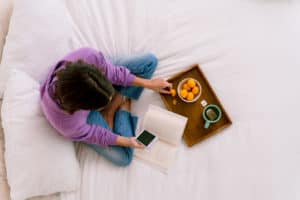 Young person sitting on bed using smartphone