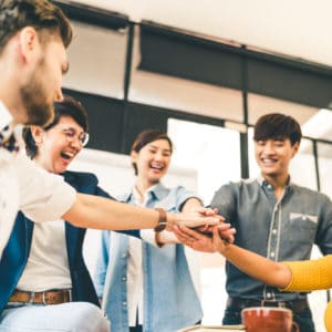 Multiethnic diverse group of happy colleagues join hands together. Creative team, casual business coworker, or college students in project meeting at modern office. Startup or teamwork concept