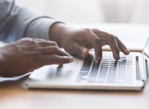 Hands of unrecognizable businessman typing on laptop keyboard in office, closeup with copy space, panorama