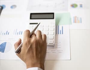 hand using a calculator on top of graph print outs