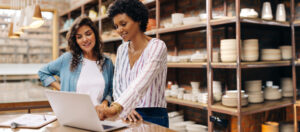 Young female ceramists using a laptop while working together. Two female entrepreneurs managing online orders in their store. Happy young businesswomen running a successful small business together.
