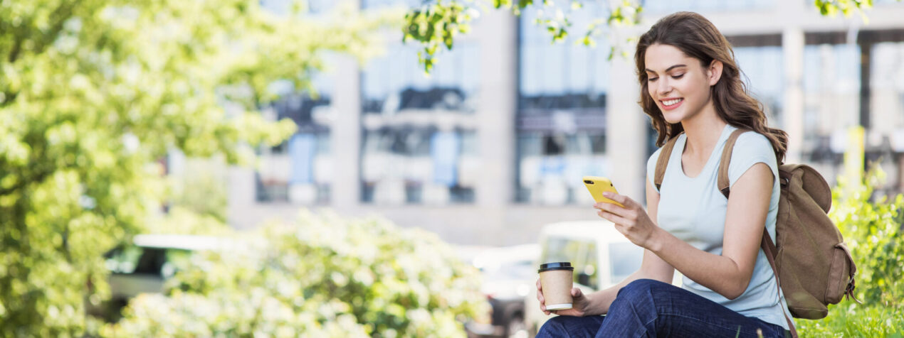 Young woman on college campus using smartphone